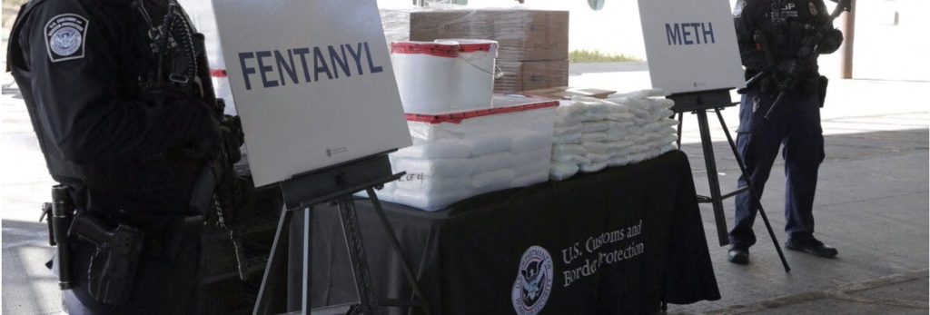 DEA agents standing next to seized fentanyl and methamphetamine