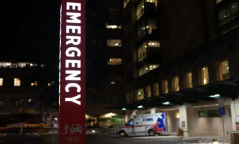 image of a Portland hospital with large, bright emergency sign at night