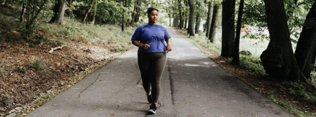 Overweight woman walking through a park for exercise